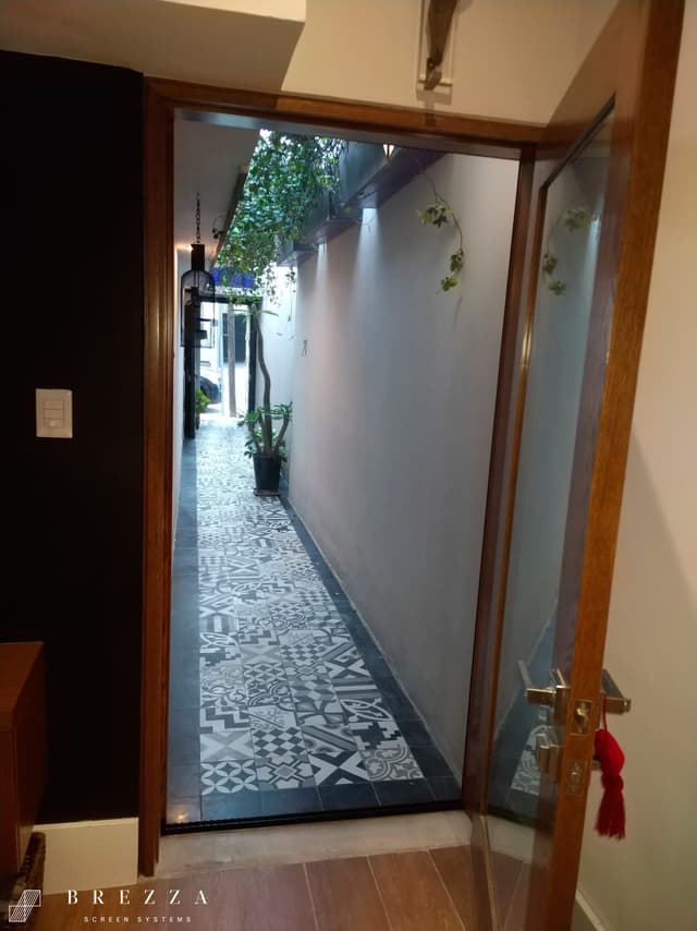 Vista frontal de un Brezza Mosquitero tipo Astuto marrón en una puerta delantera