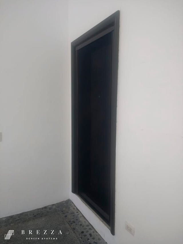 Vista lateral de un mosquitero Brezza negro con el tipo Astuto instalado en una puerta